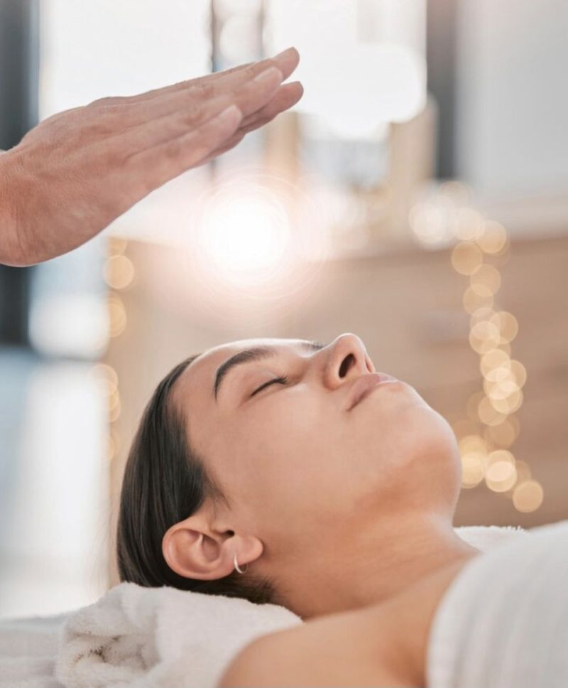 Schwebende Hand mit Sonnenuntergang über Frau bei einem REIKI Kurs